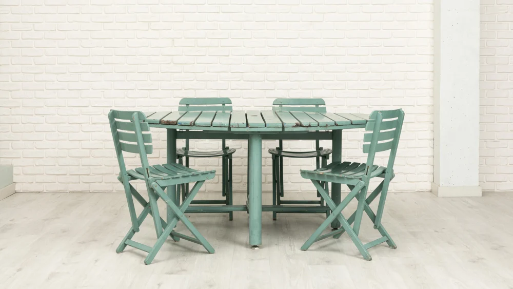 Muebles de jardín formados por una mesa y cuatro sillas de madera en color azul, tanto las sillas como la mesa plegables