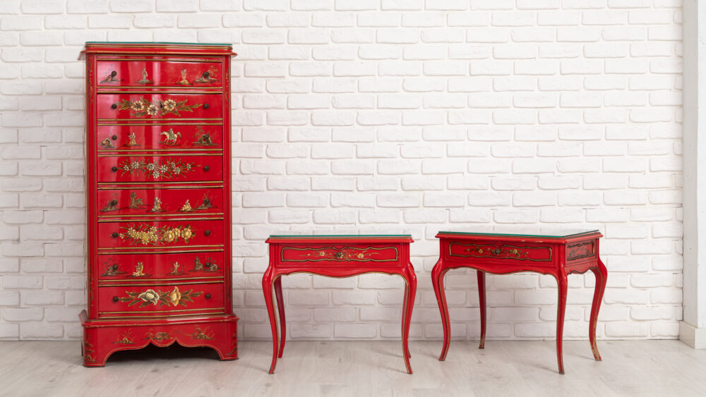 Conjunto de muebles chinos lacados en rojo con decoración dorada, cómoda alta y dos mesas auxiliares